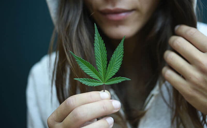 Where does CBD come from-Young woman holding a cannabis leaf