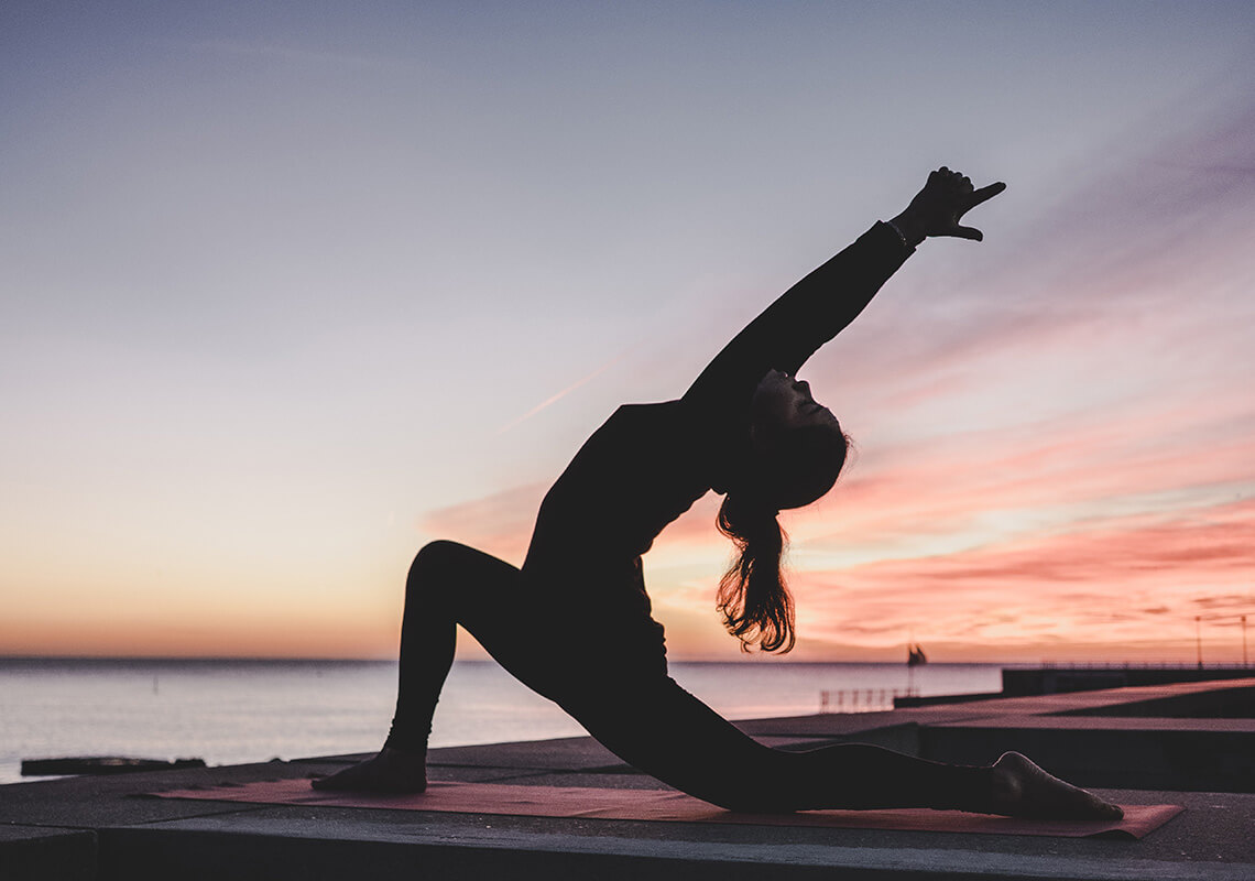 woman doing yoga in front of sunset