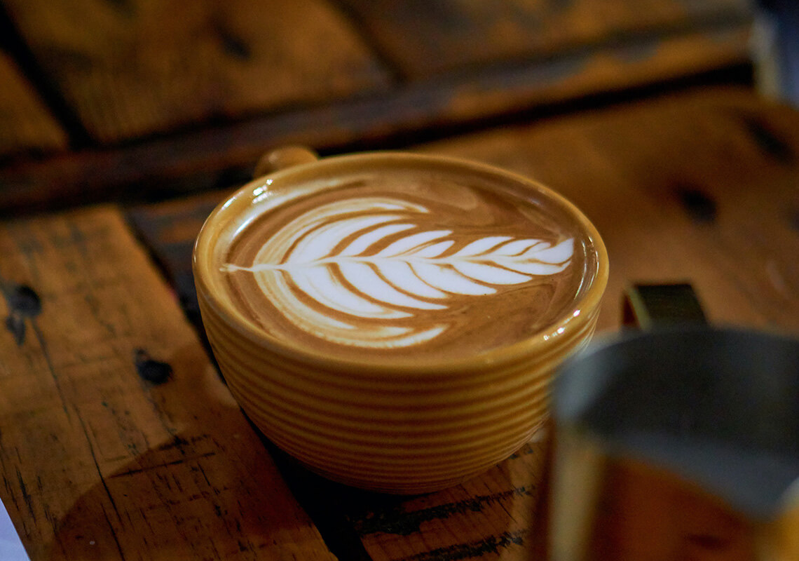 latte in yellow coffee mug on wooden table 