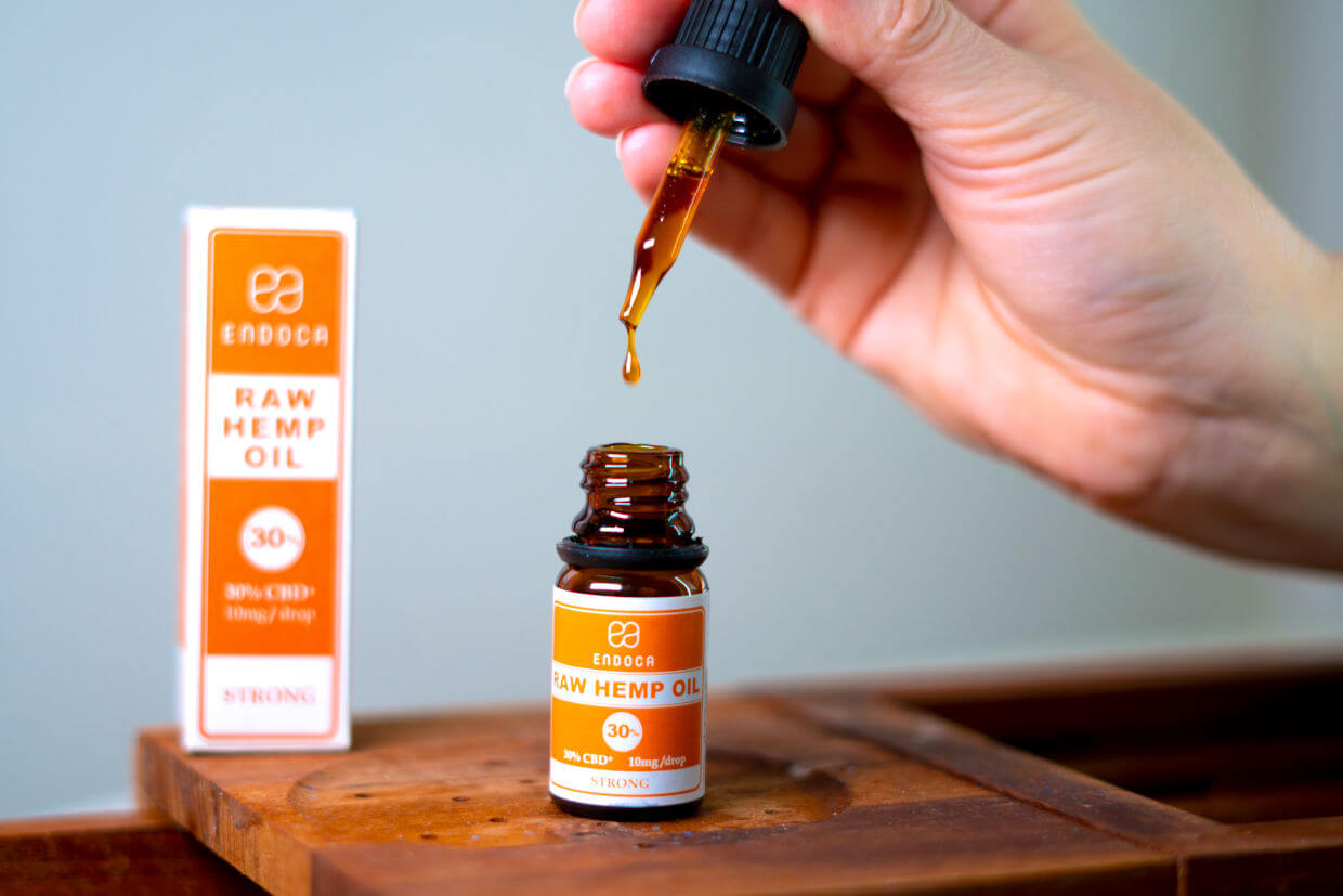 Open bottle of 30% CBD drops in orange and white packaging on wooden table