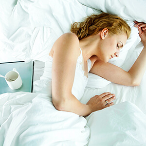 woman lying in white bed on her side