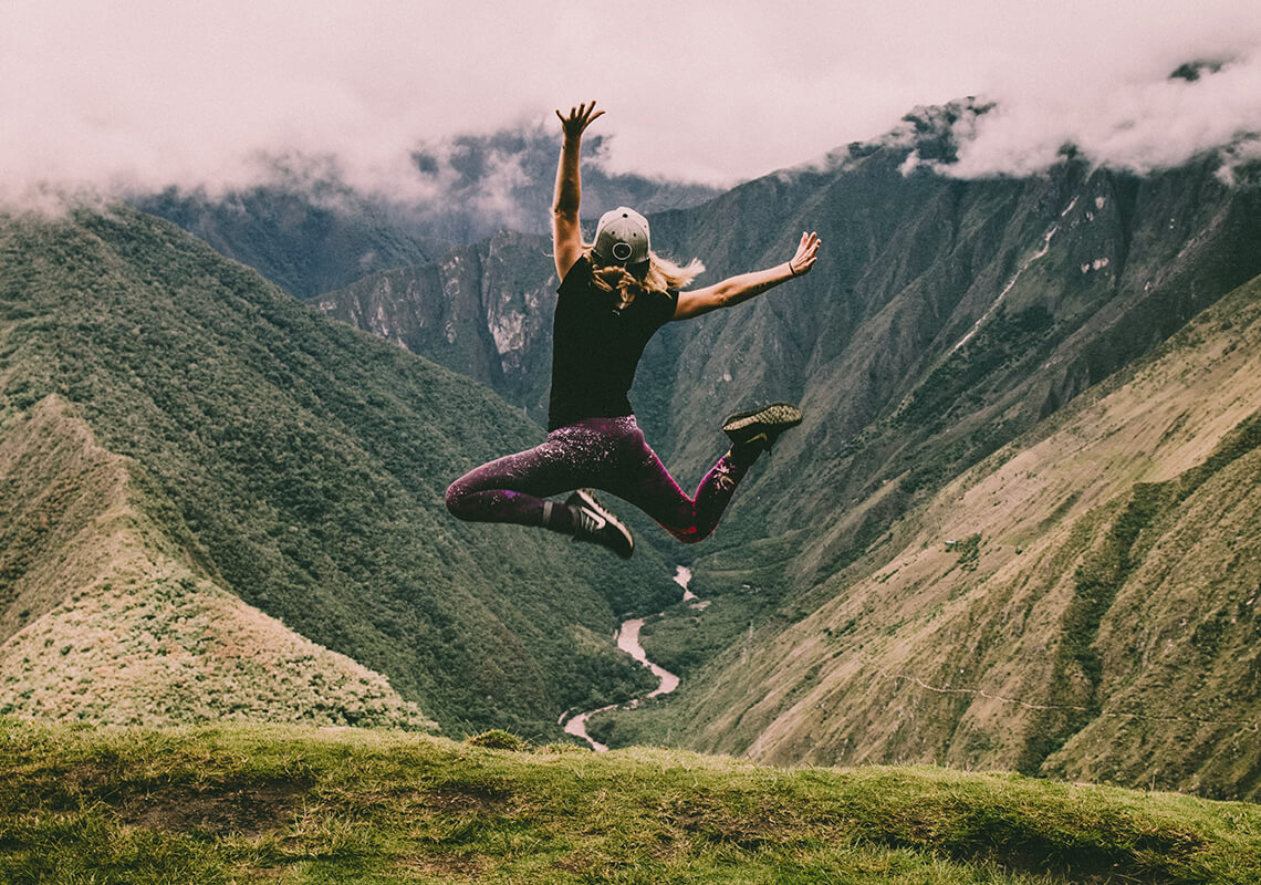 Girl jumping in air overlooking mountains