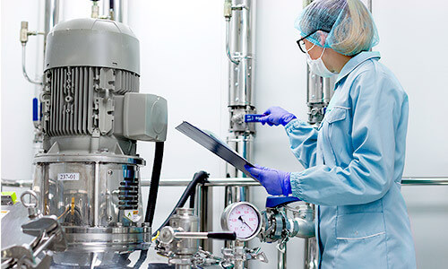 Woman checking grey machinery in blue clothes