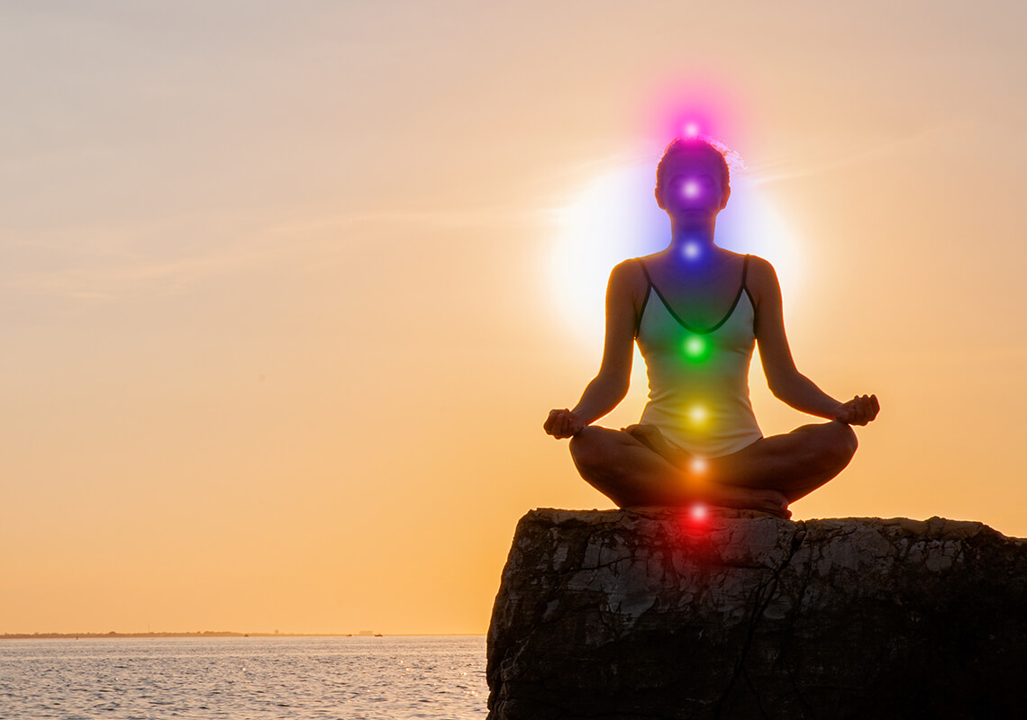 woman meditating on rock with chakras aligned