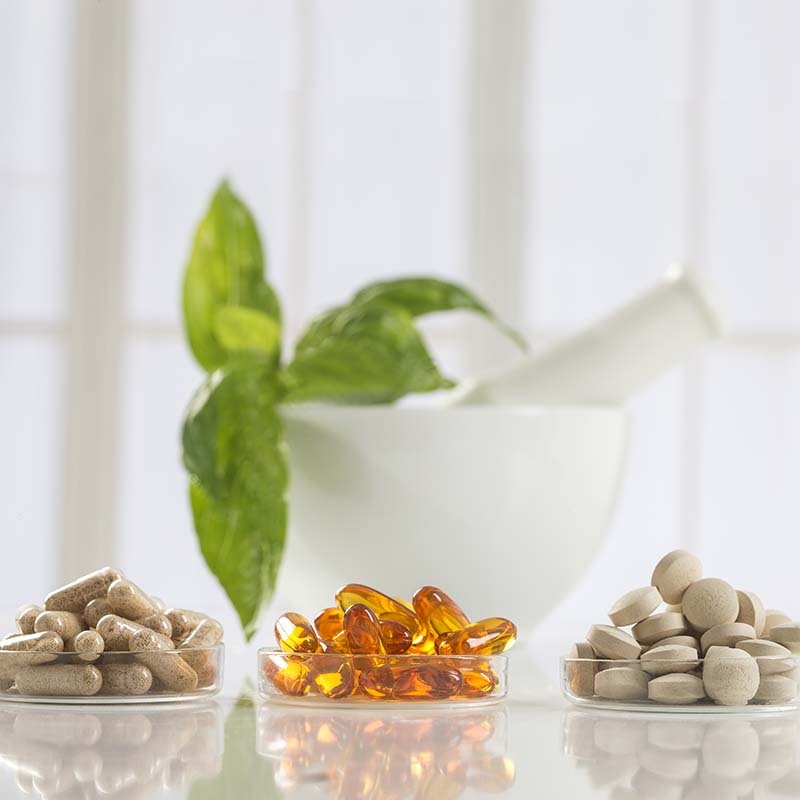 Vitamin capsules on a table with a plant behind them