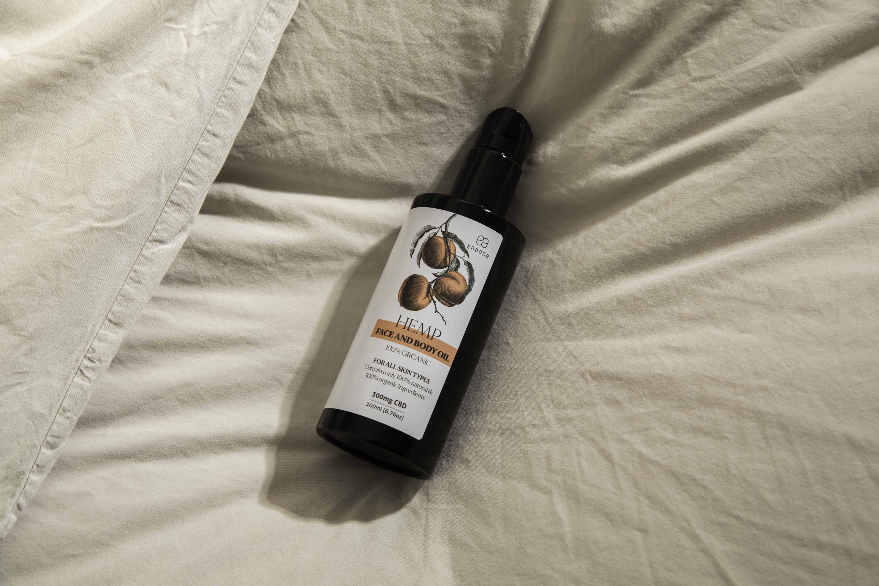Endoca hemp face and body oil bottle lying on white bedding