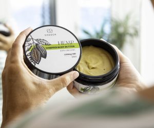 Hand holding an open tin of Endoca hemp whipped body butter