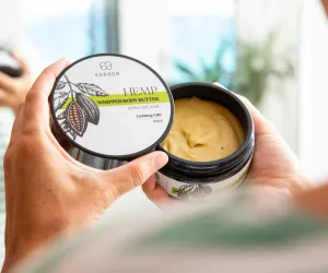 Hand holding an open tin of Endoca hemp whipped body butter