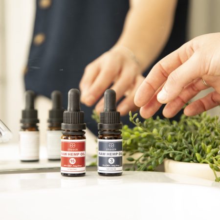 Row of Endoca CBD oil dropper bottles next to fresh hemp sprouts on a white counter